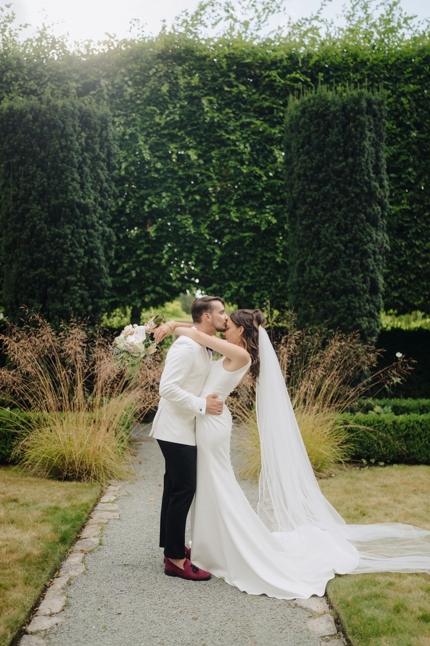 A romantic outdoor wedding scene with a flowing white dress and garden path surrounded by lush greenery.
