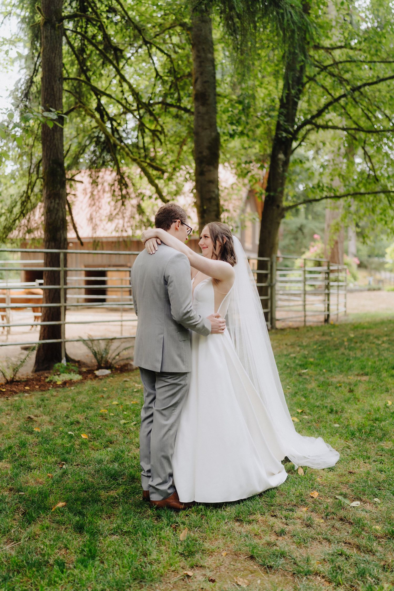 Romantic wedding couple shares intimate moments in a lush green garden setting with wooden fences.