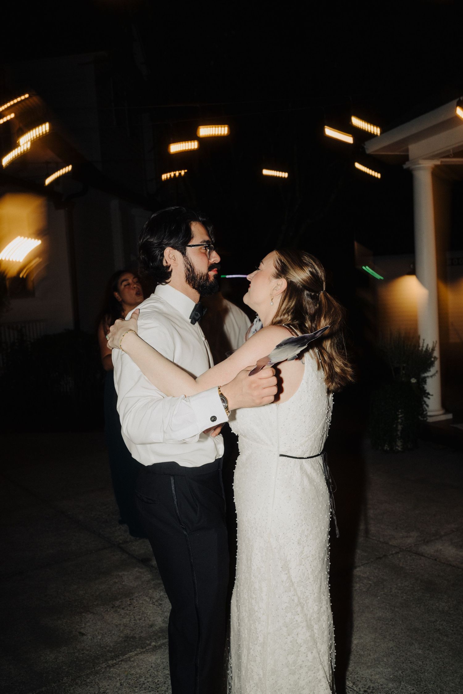 A couple sharing their first dance at an evening wedding reception under ambient lighting.