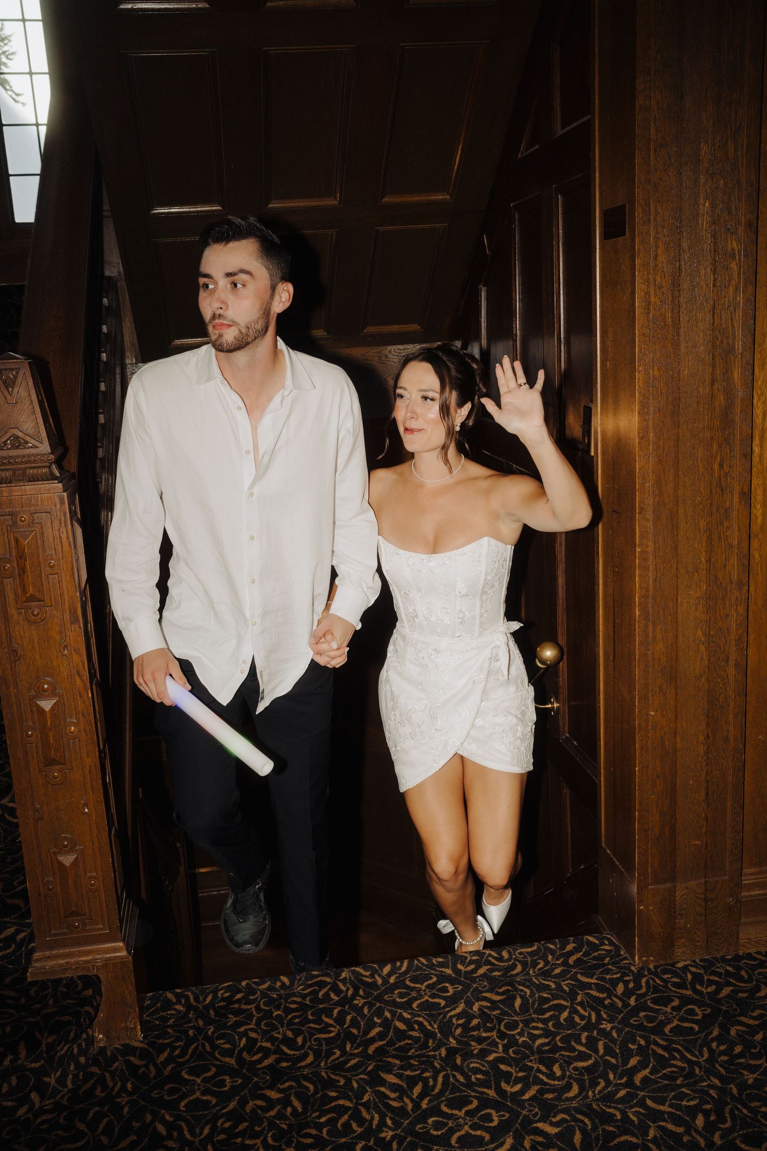 Wedding couple in casual attire walking through wooden hallway with vintage decor.