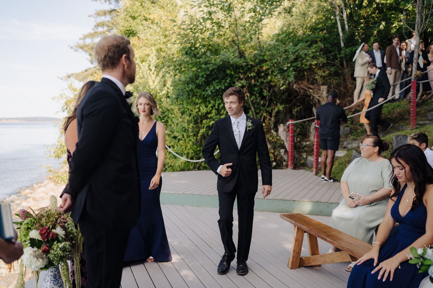 Guests gathered on a waterfront deck during an outdoor wedding ceremony.