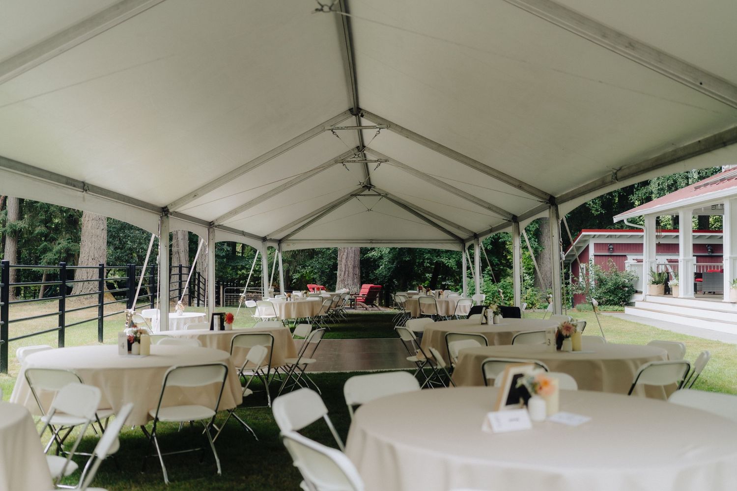 A white event tent is set up with tables and chairs for an outdoor celebration.