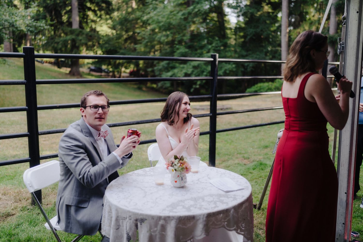 Wedding guests seated at outdoor reception tables near black fence.
