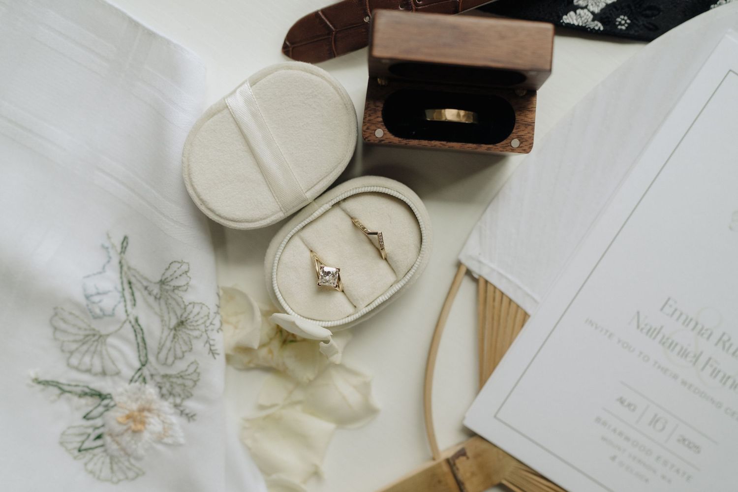 Wedding rings and jewelry displayed on white ceramic dishes with delicate floral details and a wooden box.
