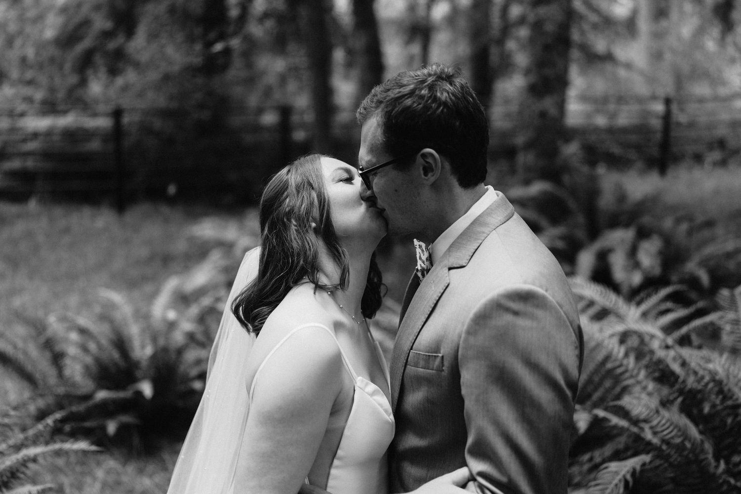 A romantic black and white portrait of newlyweds sharing an intimate moment in a forest.