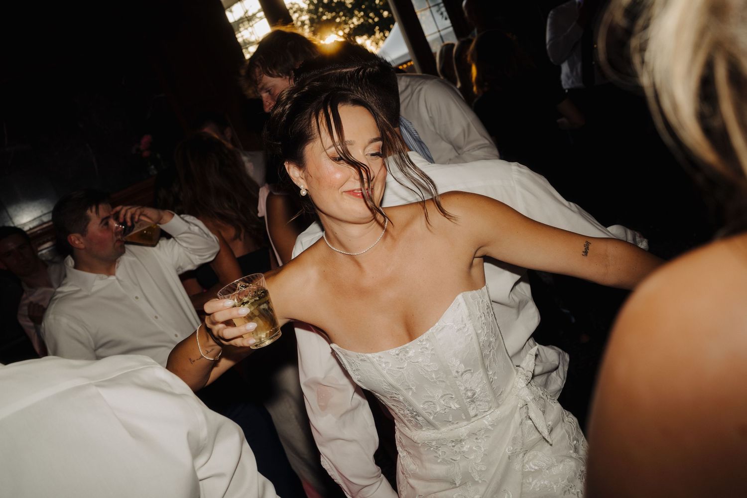 Energetic dancing at a wedding reception with guests celebrating on a dark dance floor.