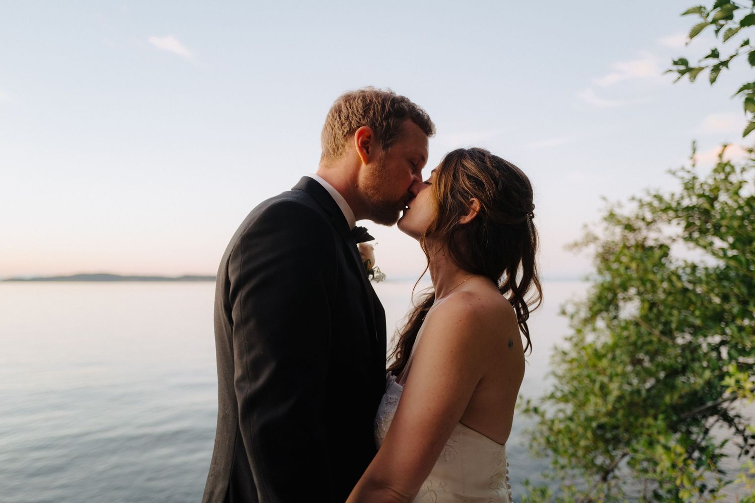 Romantic sunset wedding portrait session with couple embracing by the water.