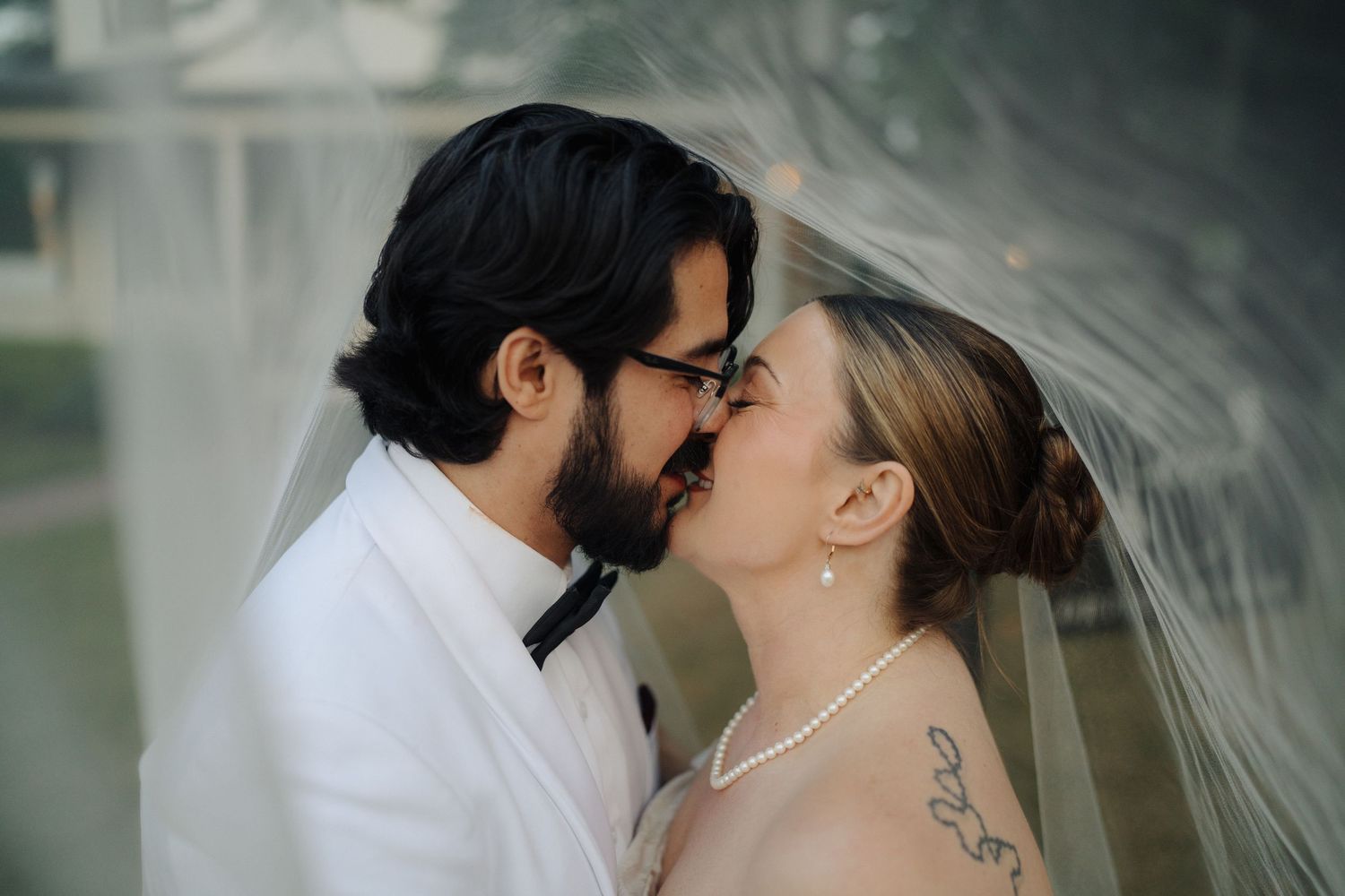 Close-up romantic wedding moment captured with artistic lighting and veil details.