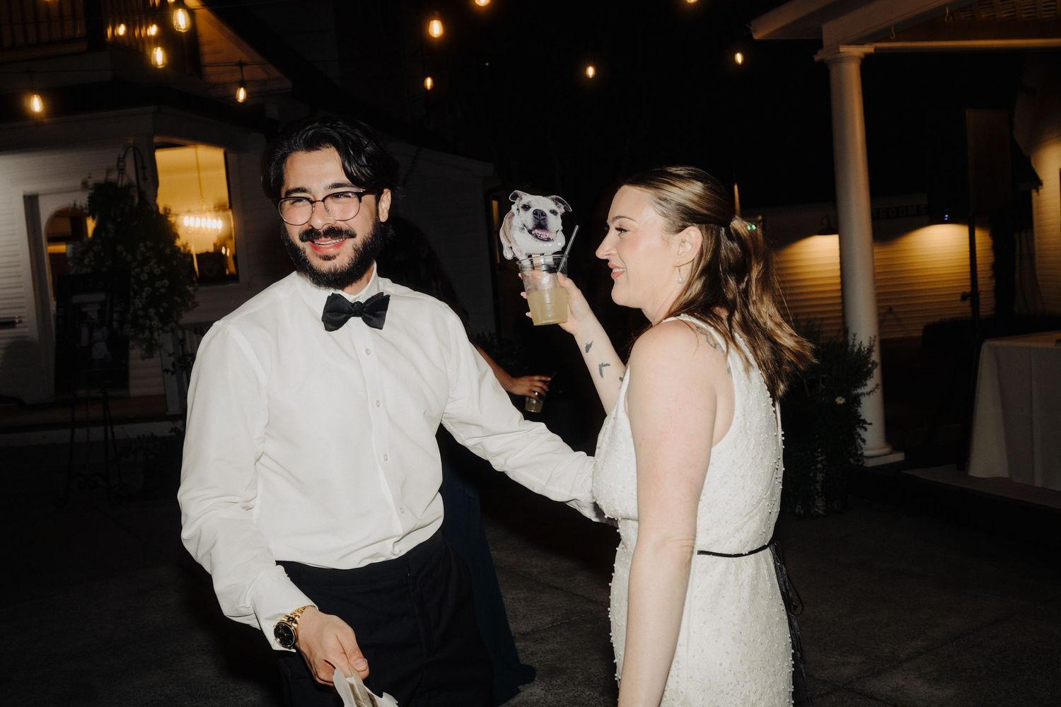 Wedding guests dancing and celebrating at an evening reception under string lights.