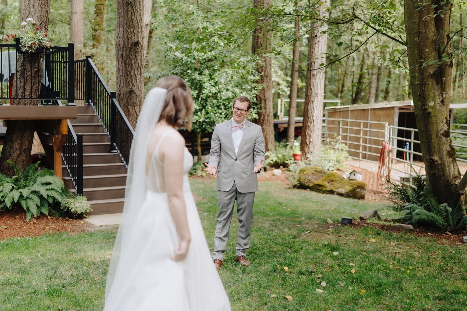 A couple shares a romantic moment during their outdoor forest wedding ceremony surrounded by tall trees.