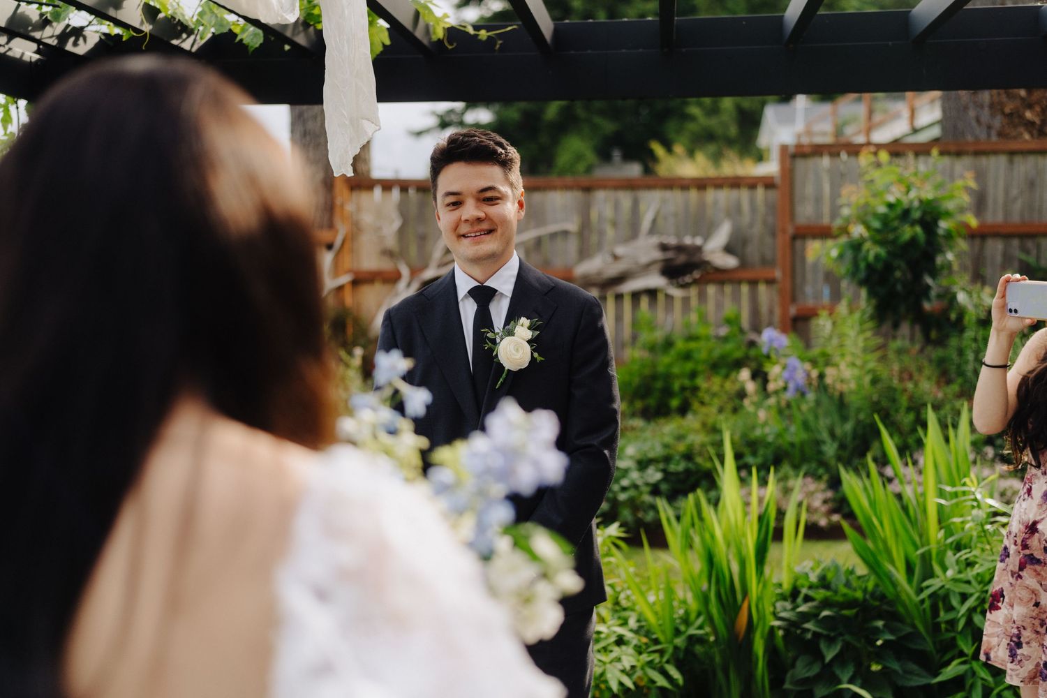 Outdoor garden wedding scene with beautiful spring flowers and greenery in the background.