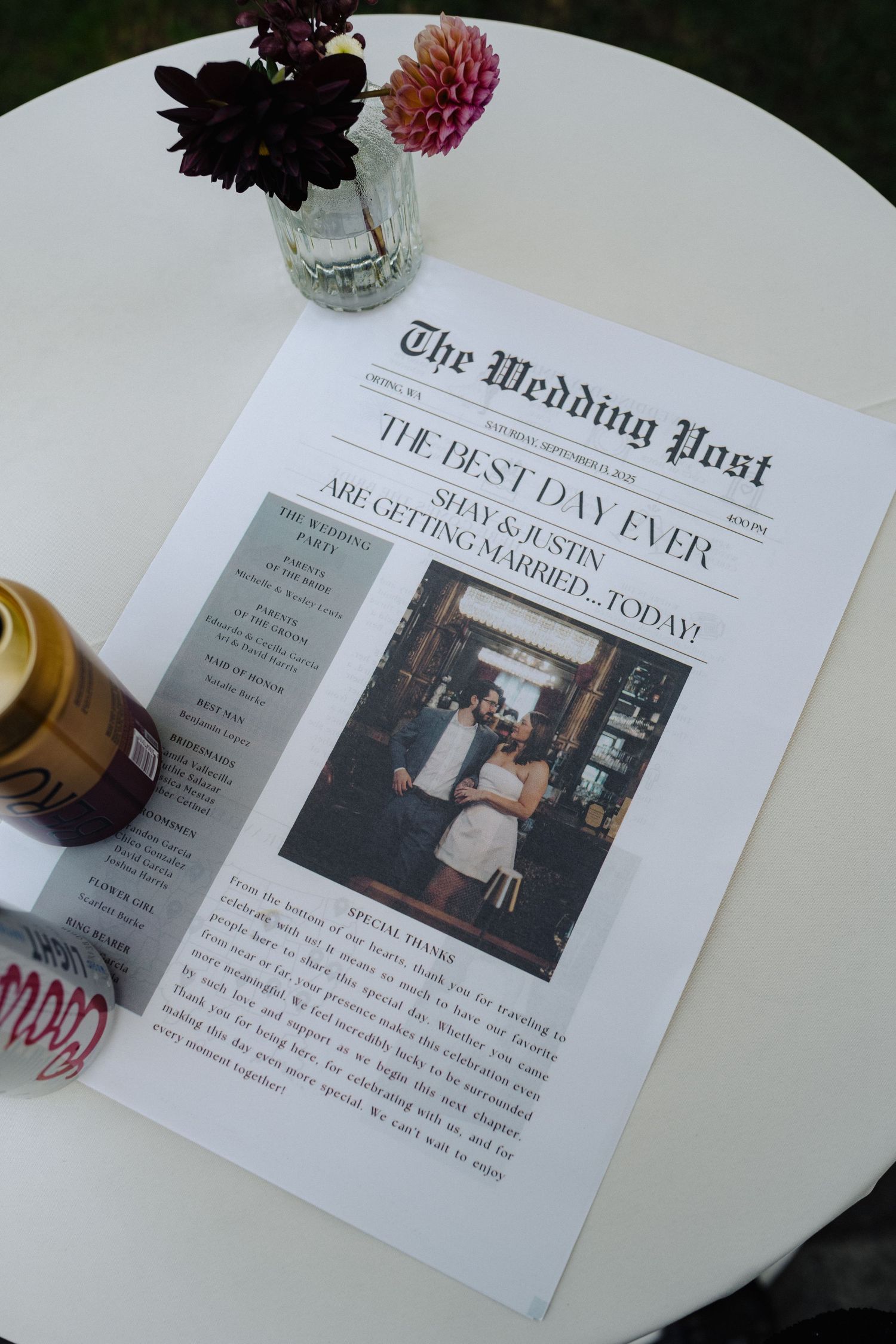 Wedding-themed newspaper layout with black and white photos displayed on a white table with floral decorations.