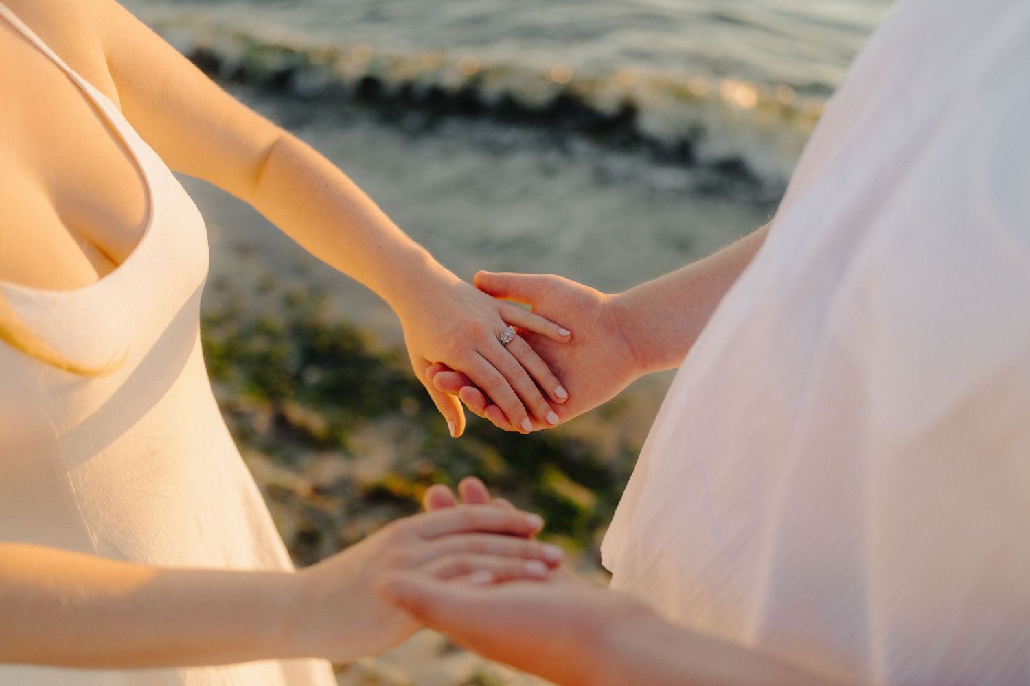 Close-up detail of hands and white dress fabric in warm sunlight.