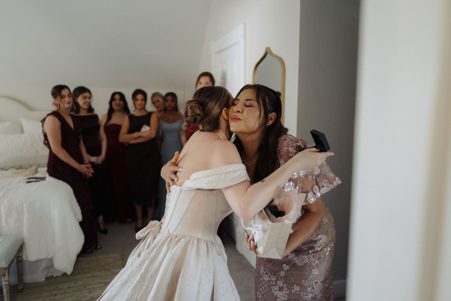 An emotional embrace between people in formal attire at an indoor wedding celebration.