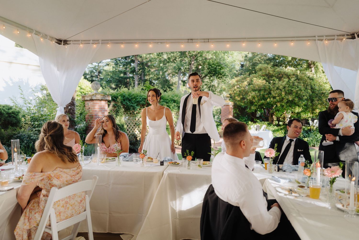 Wedding reception setup with long tables under an outdoor tent.