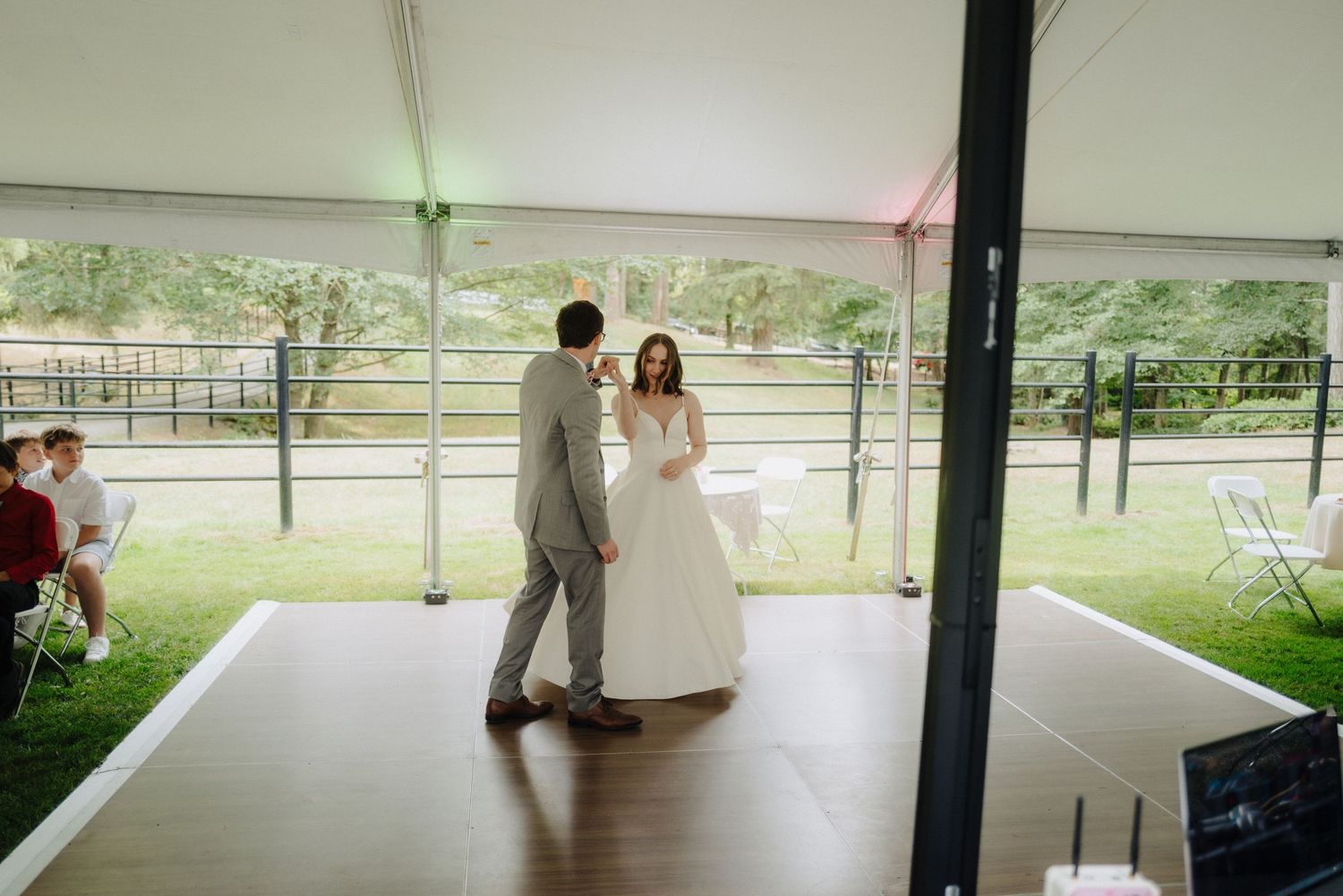 Wedding reception dance floor under white tent with soft lighting.