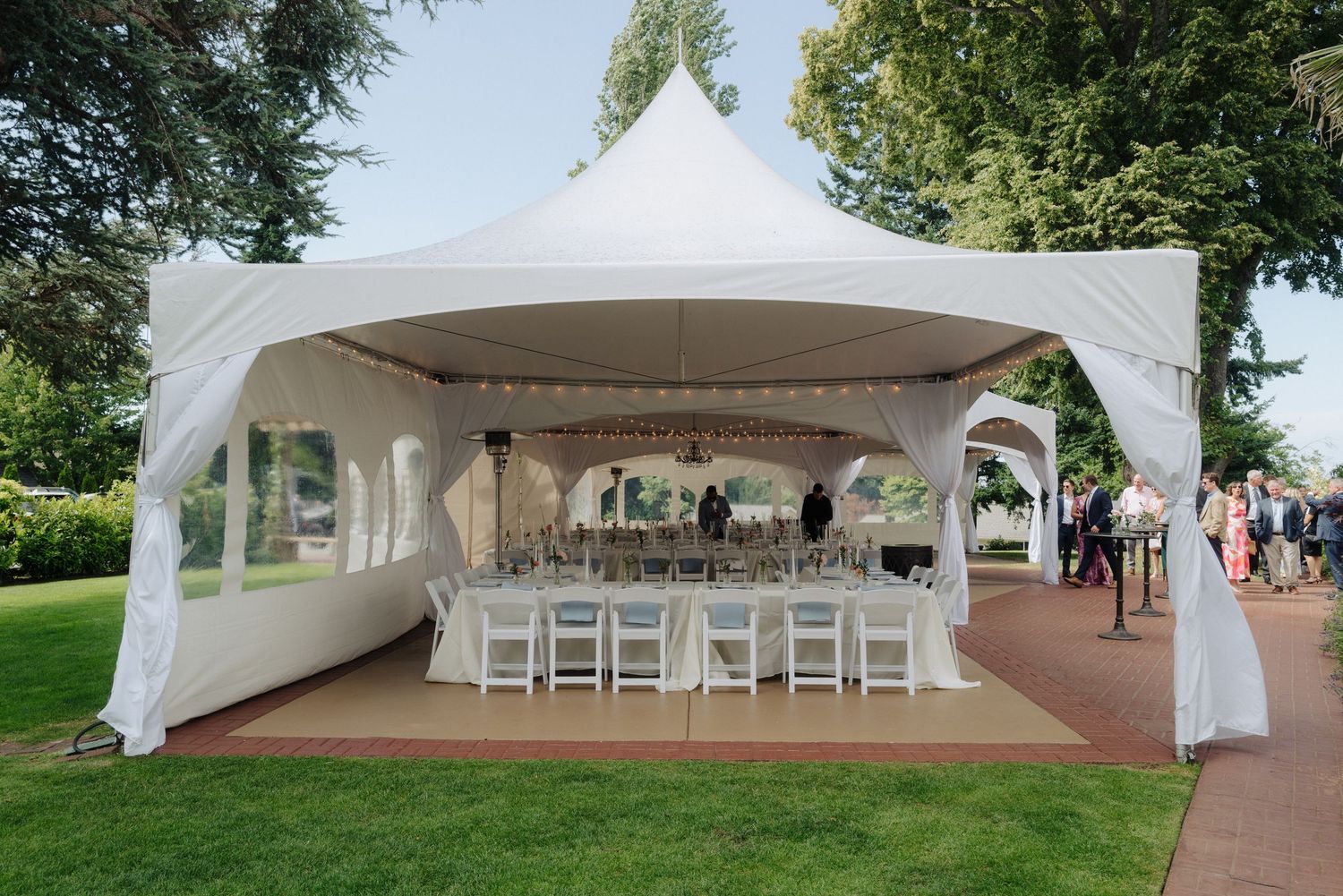 White wedding tent setup with chairs and decorations in an outdoor garden setting.