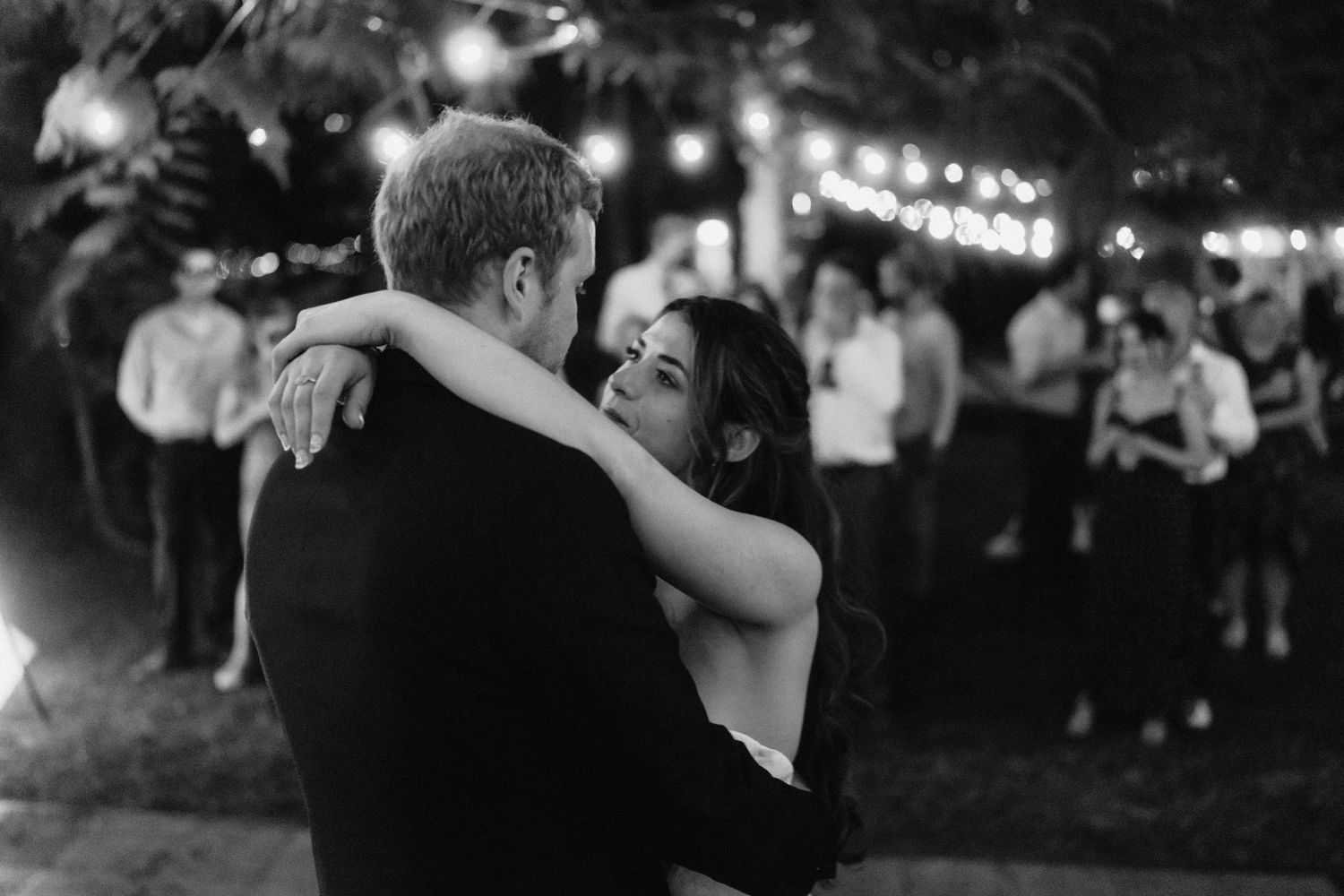 Black and white photo of evening wedding reception with string lights.