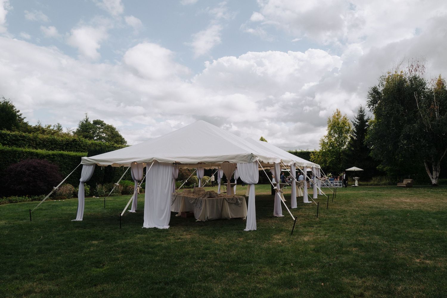 White wedding tents set up in a green field under cloudy summer skies.