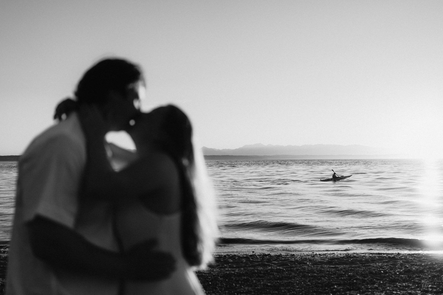 Silhouettes of a couple embracing against a moody ocean backdrop during golden hour.