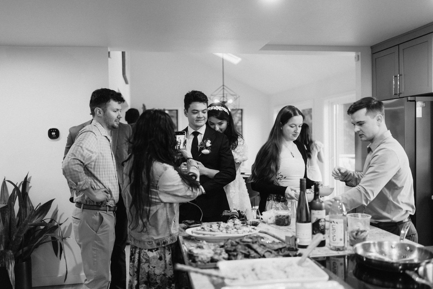 Wedding party members gather in modern kitchen space during preparations.
