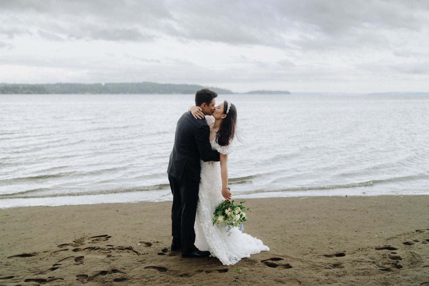 Couple shares intimate moments on a scenic beach with water views.