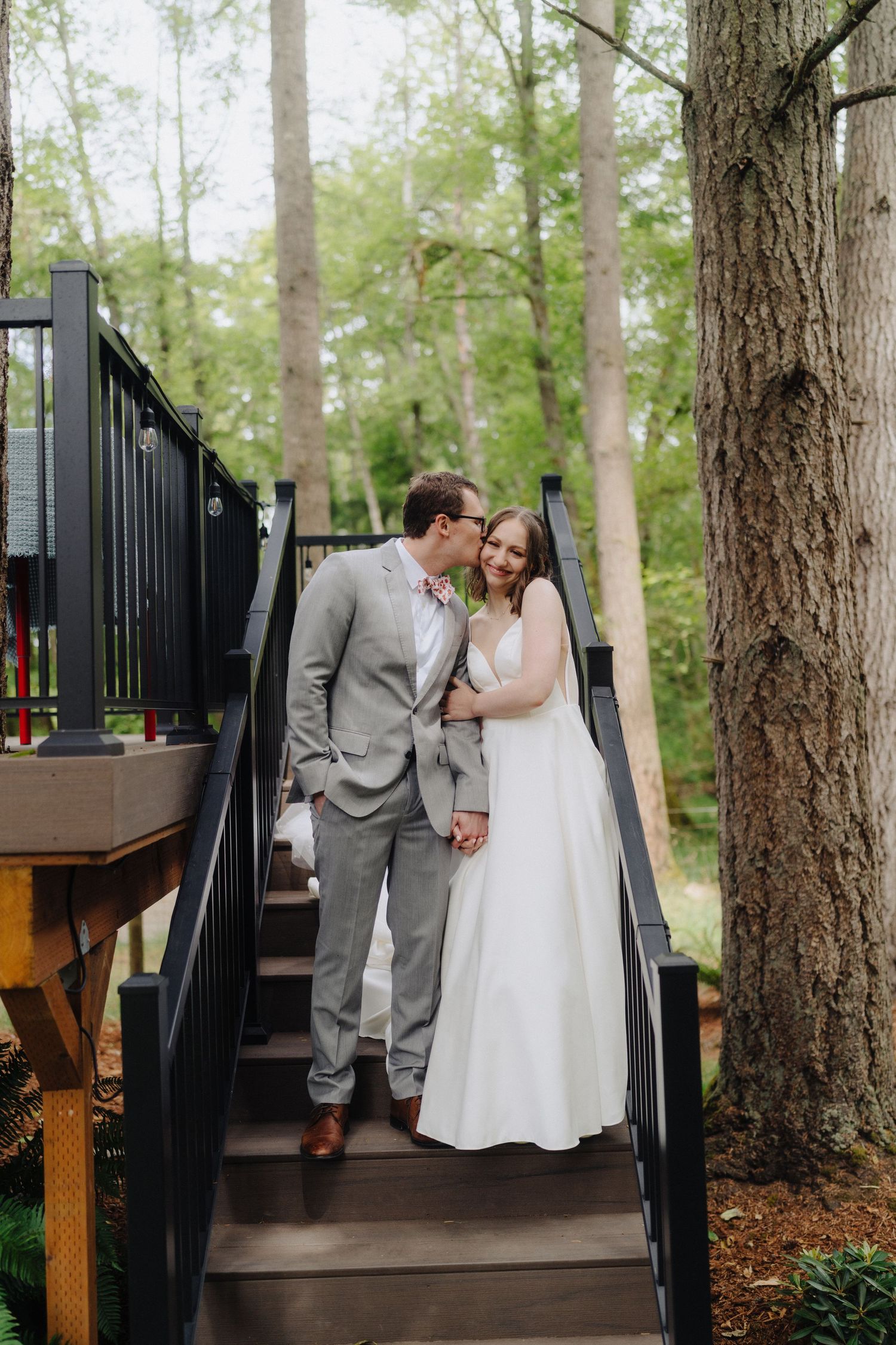 A series of intimate wedding photos taken on wooden stairs surrounded by forest trees.