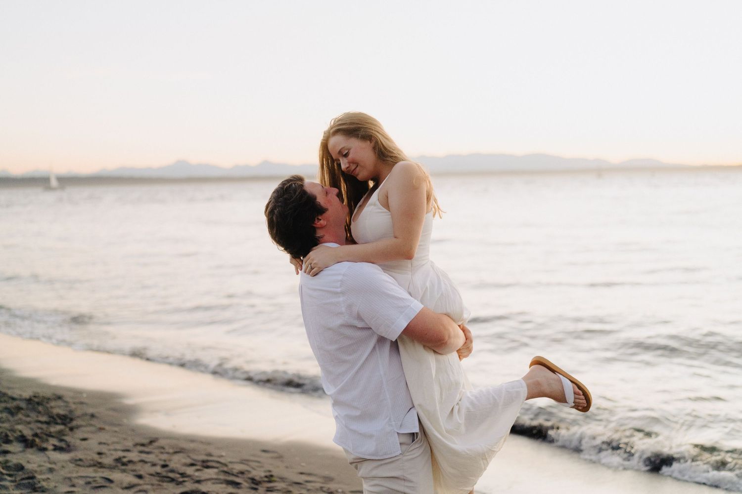 Romantic beach photoshoot with couple against sunset ocean backdrop.