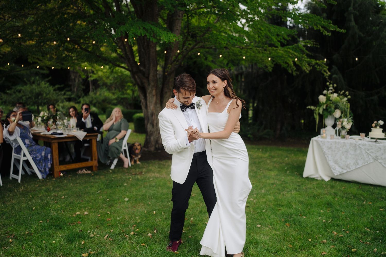 Elegant outdoor wedding celebration with guests gathered on a manicured lawn.