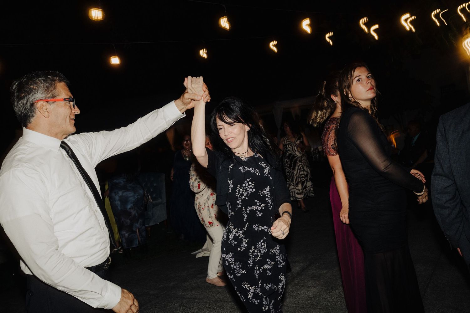 Wedding reception dance party with string lights creating a festive nighttime atmosphere.