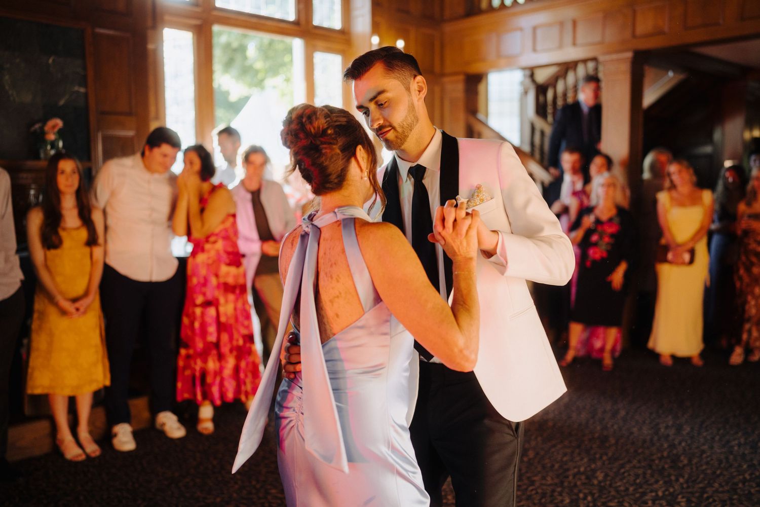 Wedding reception dance party with guests in colorful dresses.