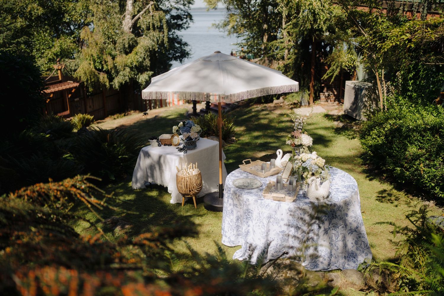 Elegant outdoor wedding reception tables decorated with white linens and floral centerpieces in a garden setting.