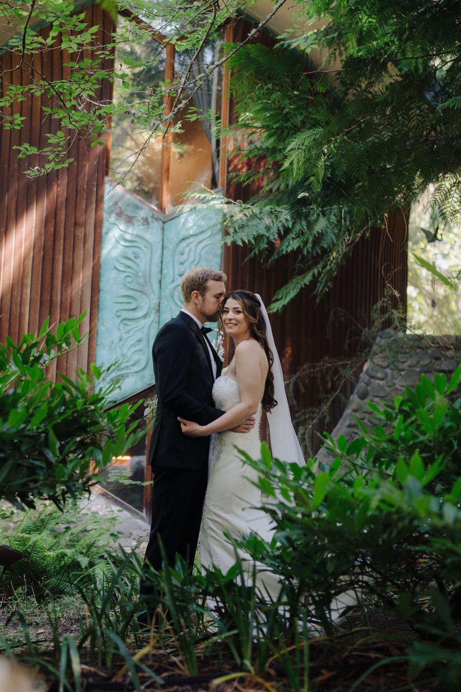 Couple shares intimate moment in a lush garden setting.