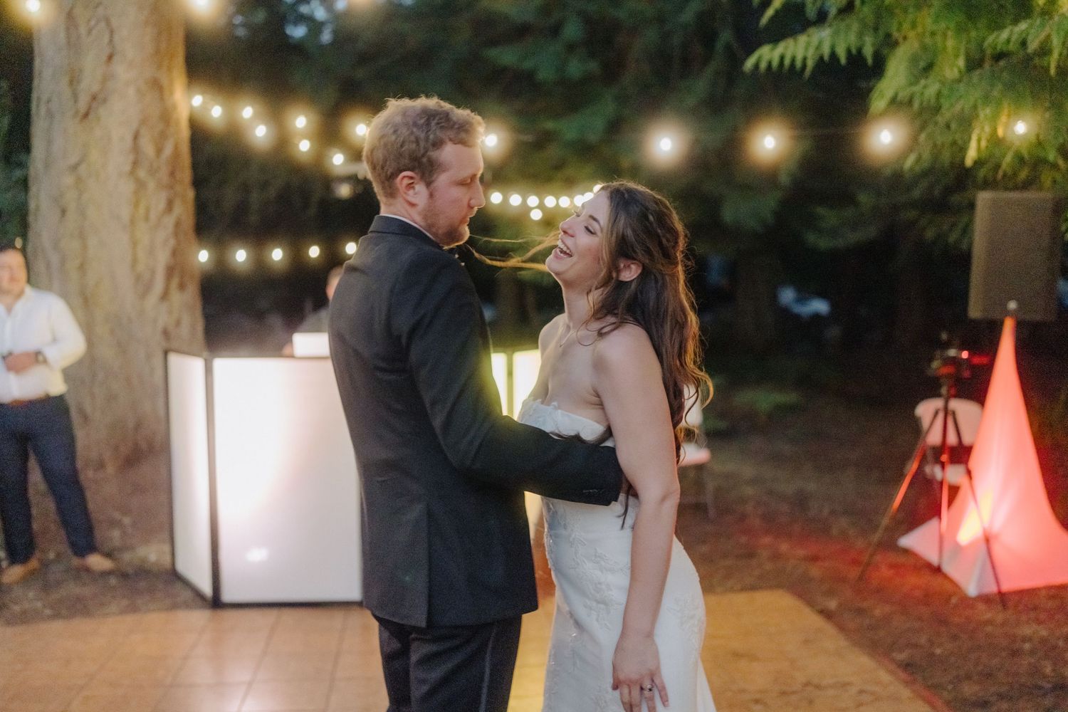 String lights illuminate outdoor evening wedding reception space.