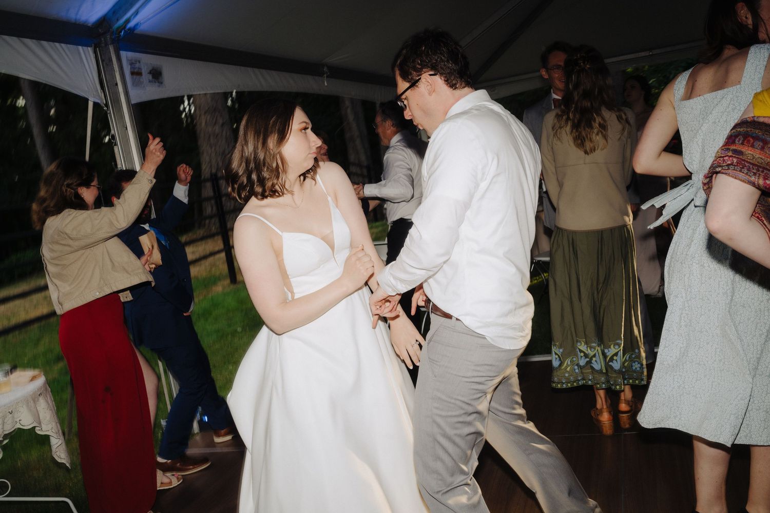 Wedding celebration under a white tent with guests dancing and enjoying the festivities.