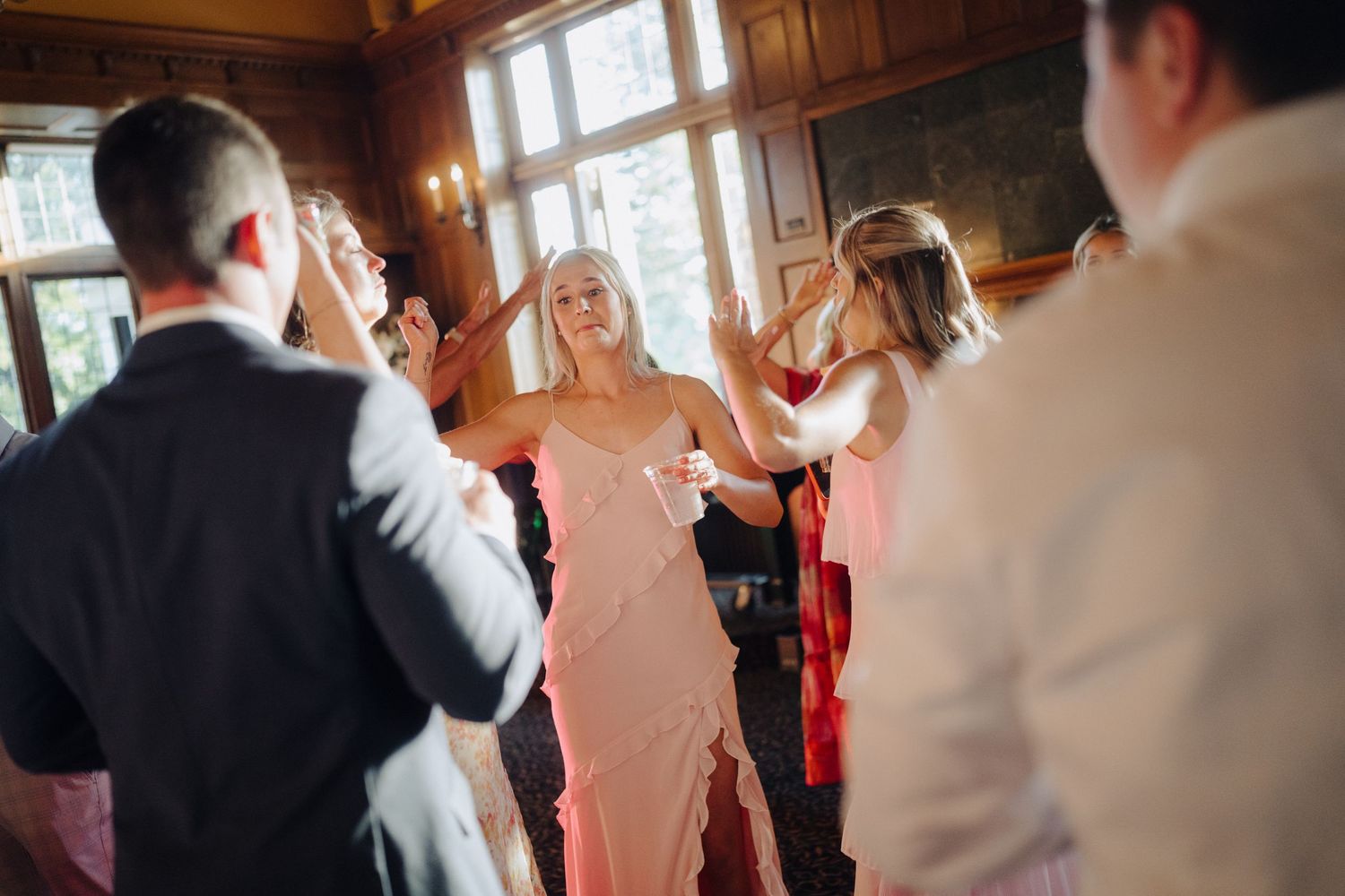 Wedding reception guests enjoying a celebration in an elegant wood-paneled room with warm lighting.