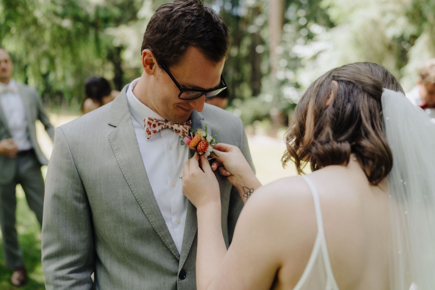 Newlywed couple shares a tender kiss during their outdoor wedding ceremony surrounded by greenery.