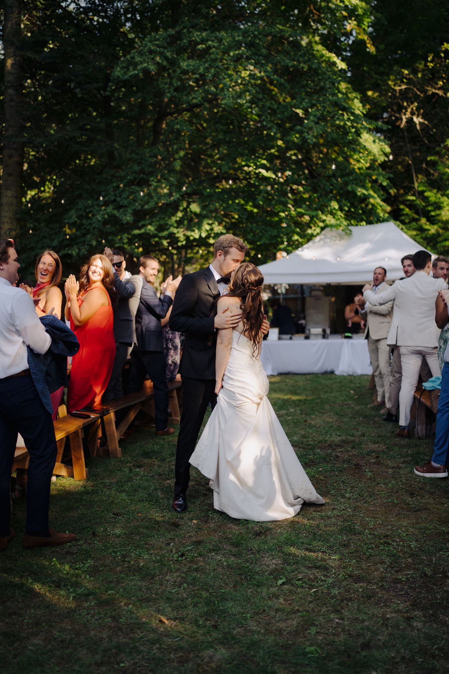 Wedding guests dancing and celebrating on a grassy lawn at an outdoor reception.