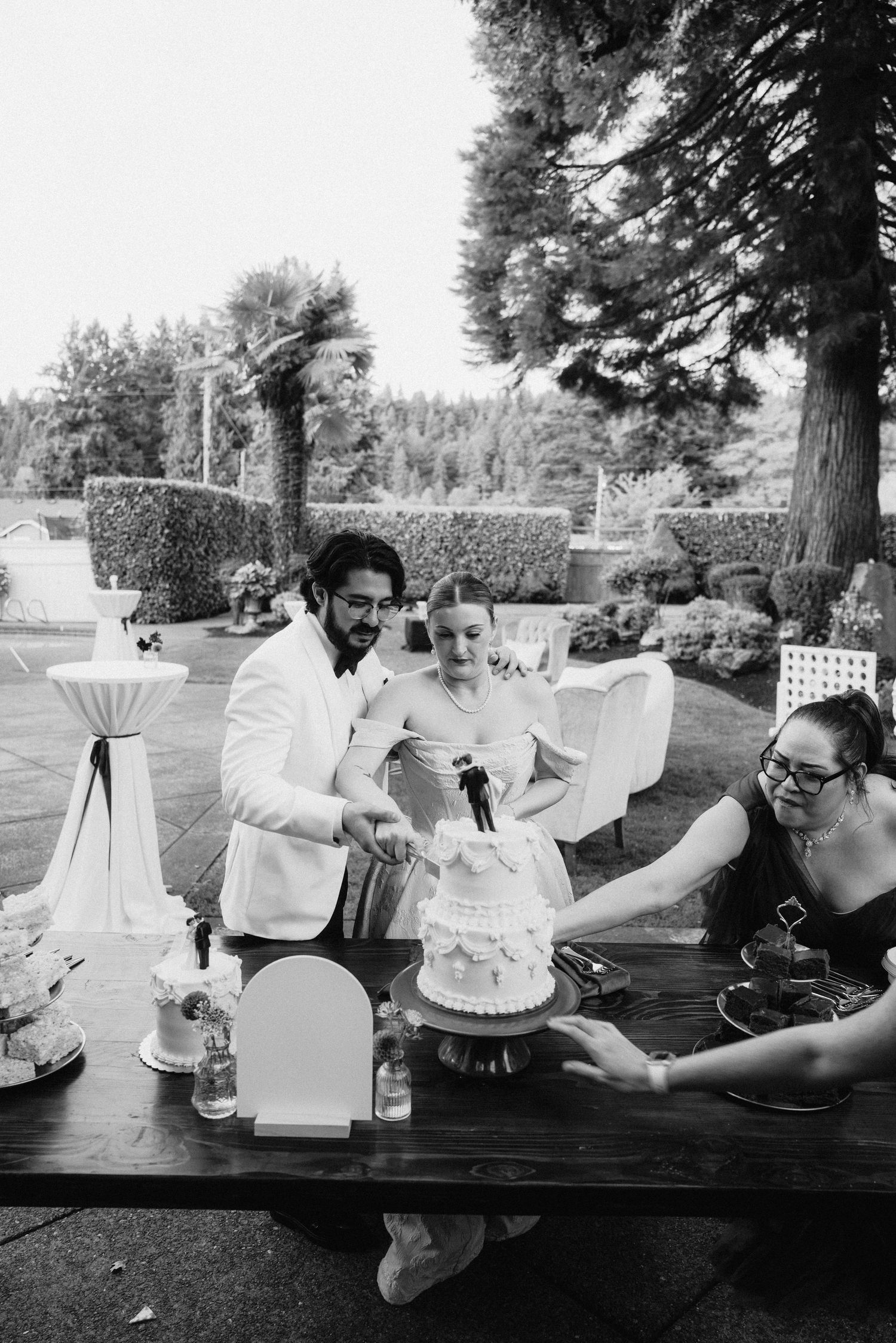 Black and white photo of outdoor cocktail tables with white linens at a garden reception.