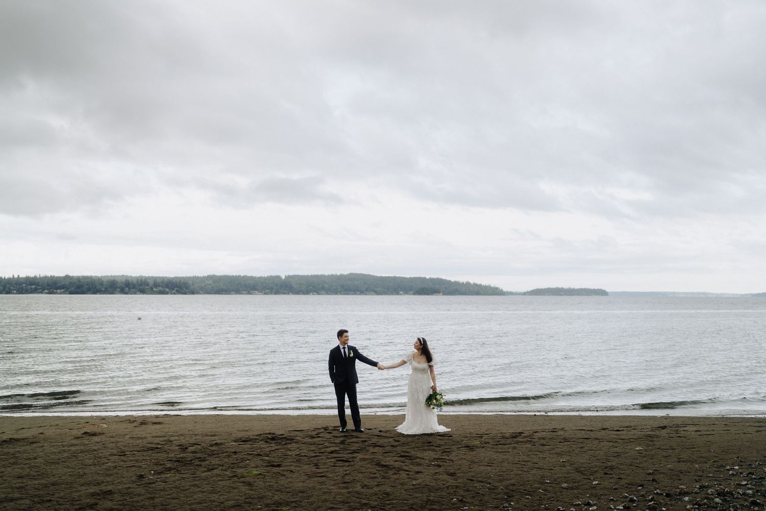 A moody beach wedding scene with overcast skies and calm waters in the background.