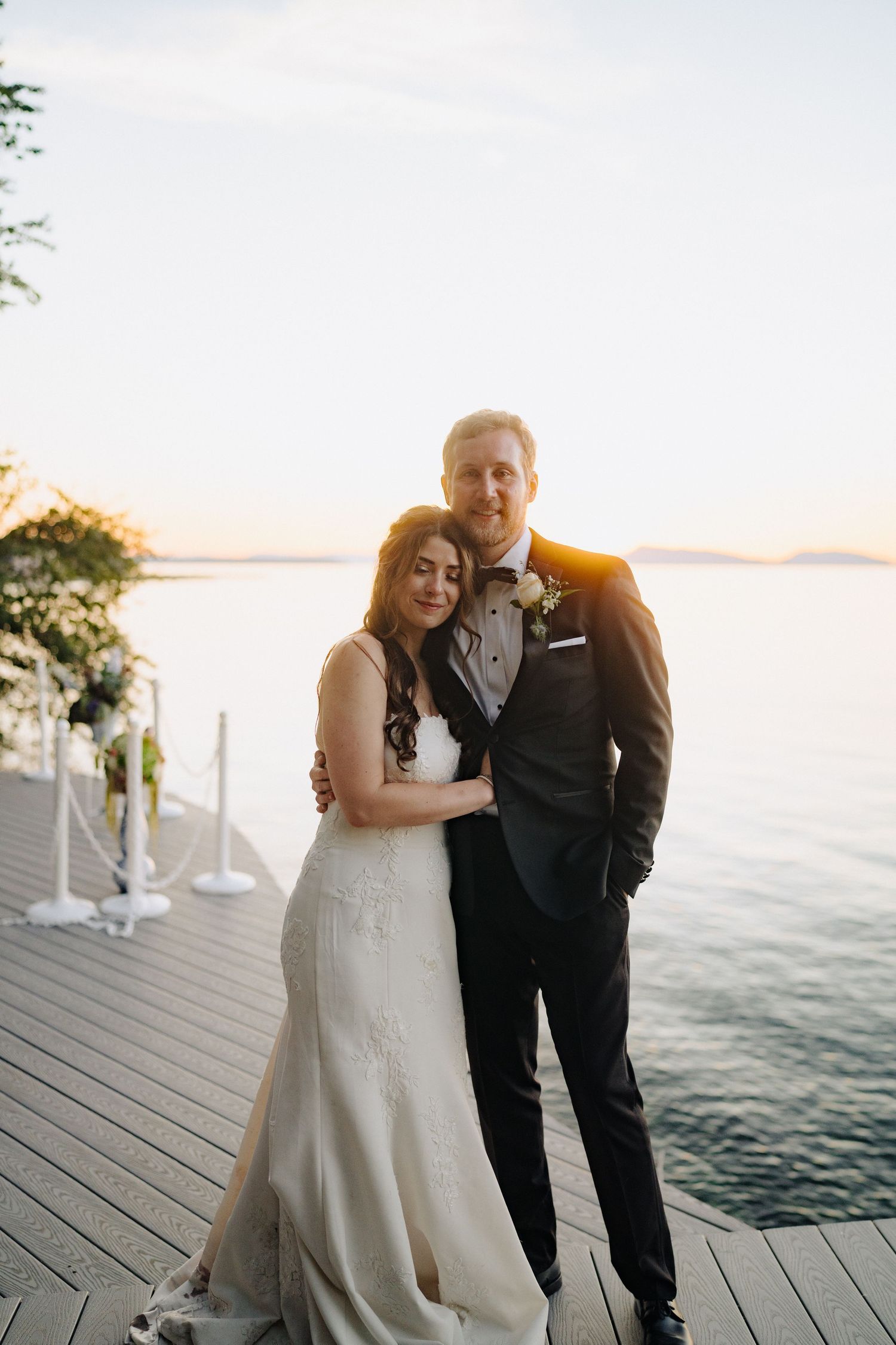 Romantic sunset wedding photos on a waterfront deck with golden hour lighting.