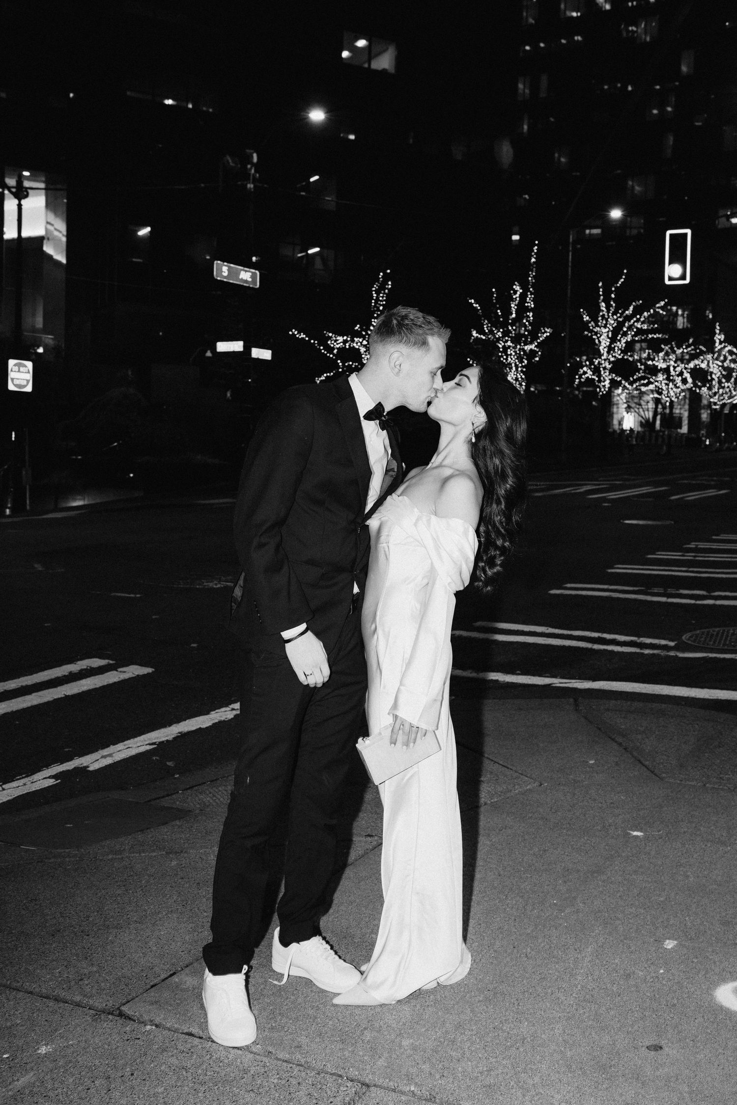 A romantic nighttime street scene with a couple sharing a kiss under city lights.