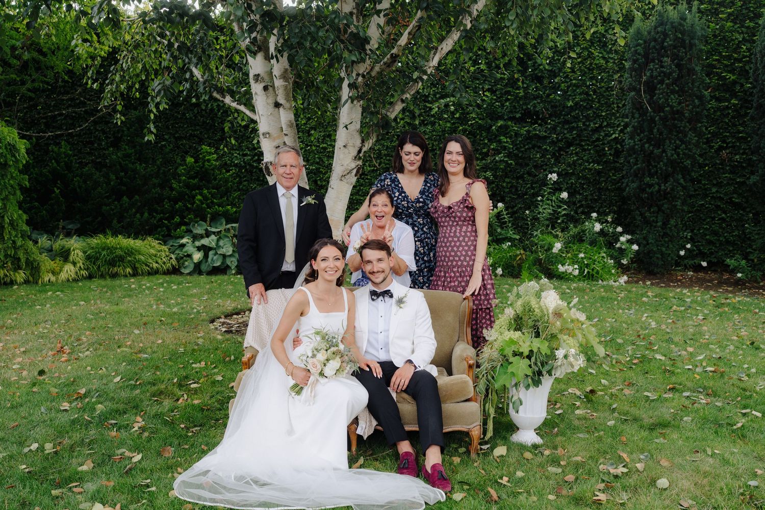 Wedding ceremony setup in a lush garden with white chairs and floral decorations.
