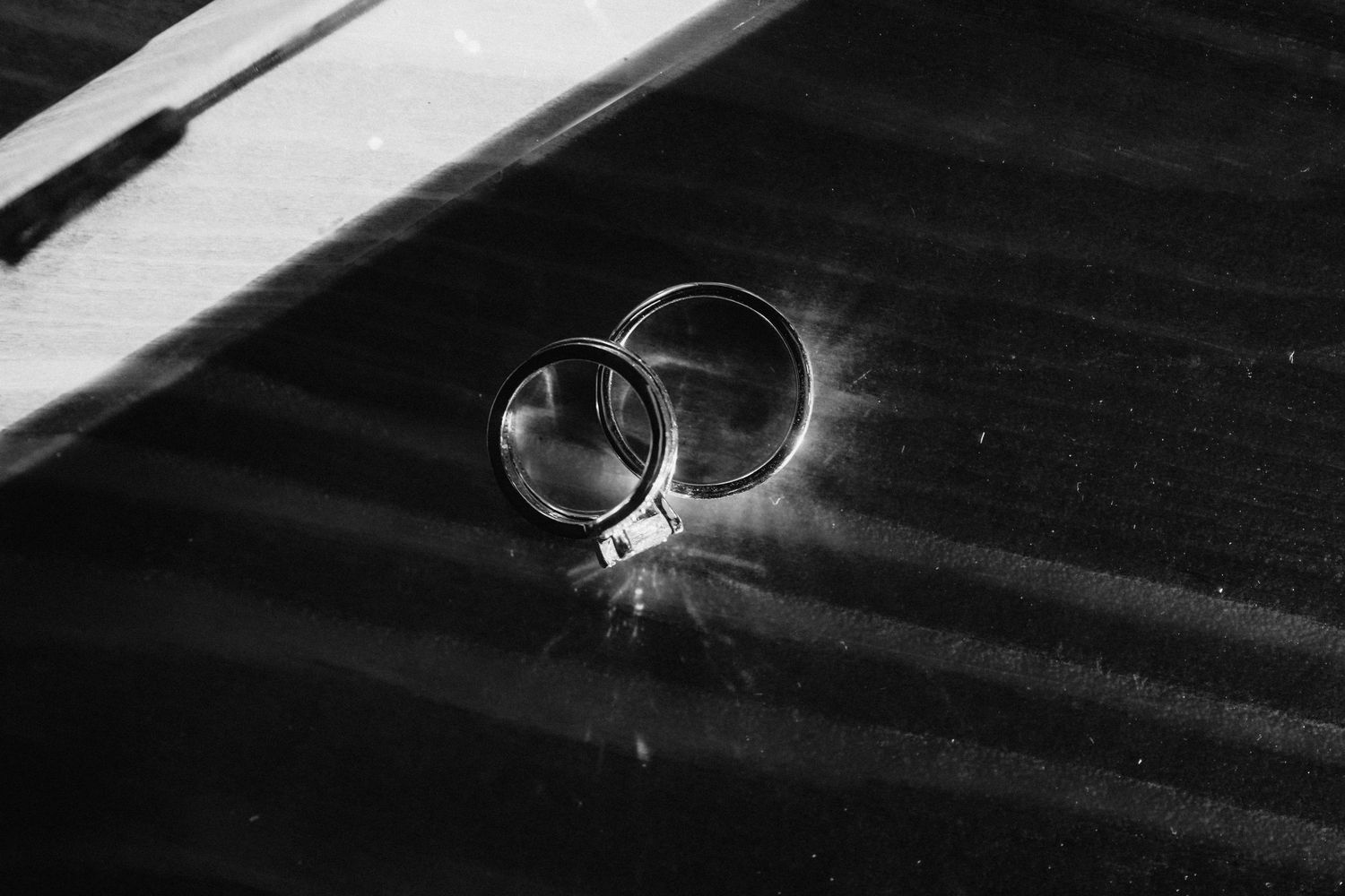 Artistic black and white detail shot of wedding rings with dramatic lighting.