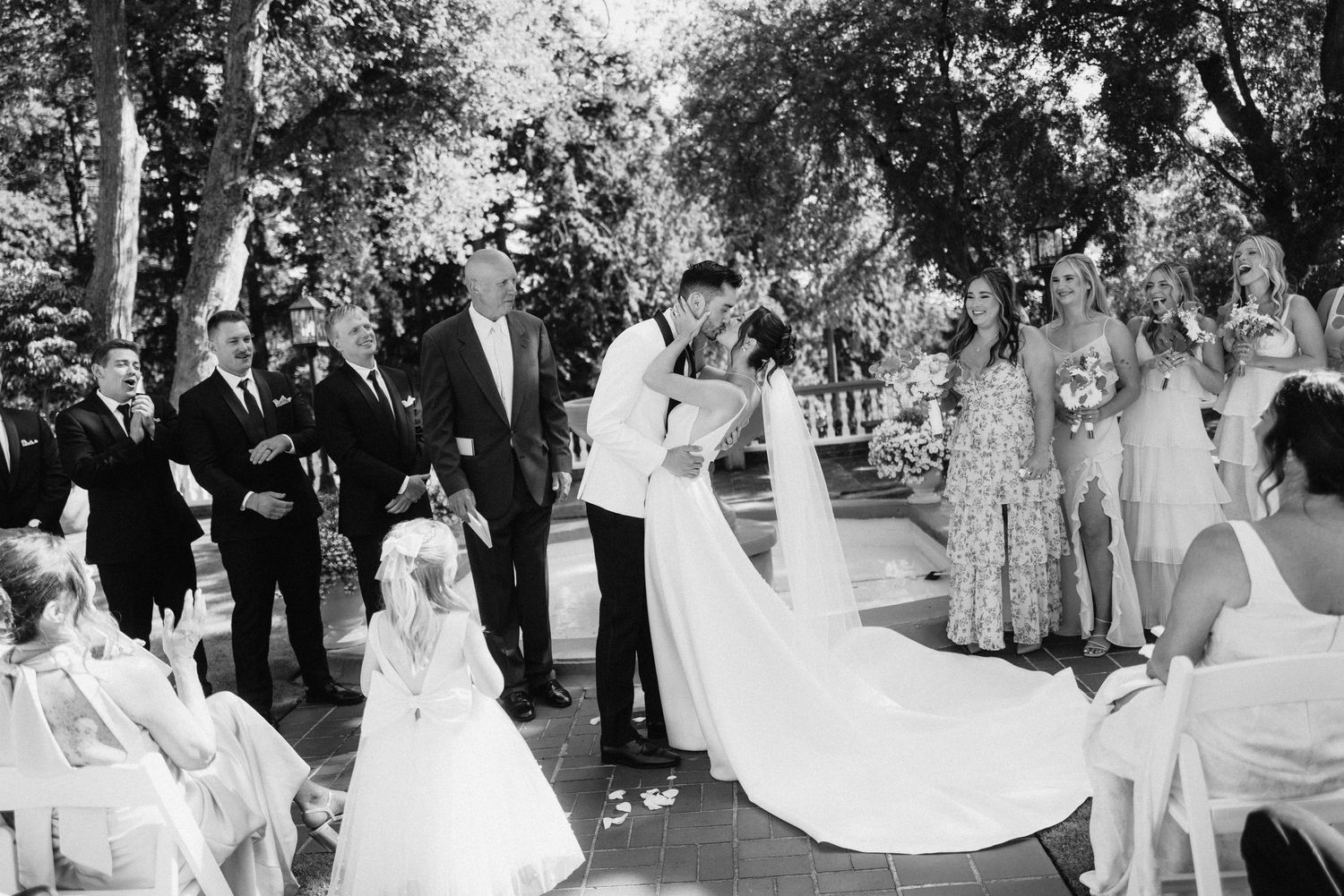 A group of wedding guests dancing together at an outdoor garden reception celebration.