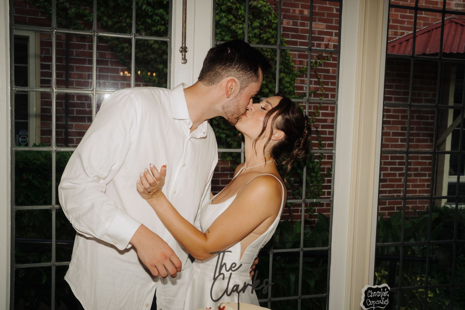A romantic evening dance moment captured through a window at an elegant brick venue.