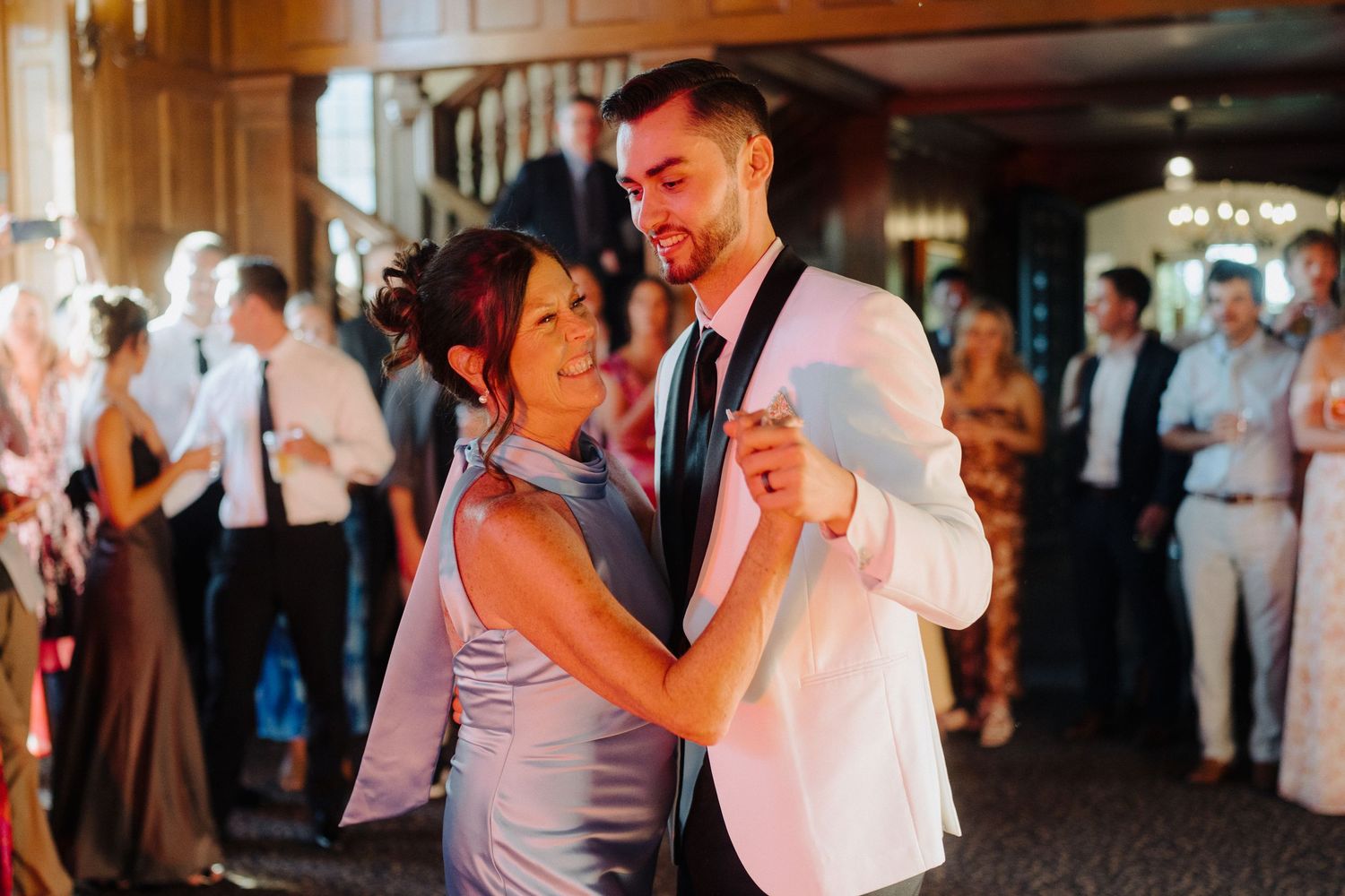 Couples slow dancing at an evening wedding reception under warm lighting.