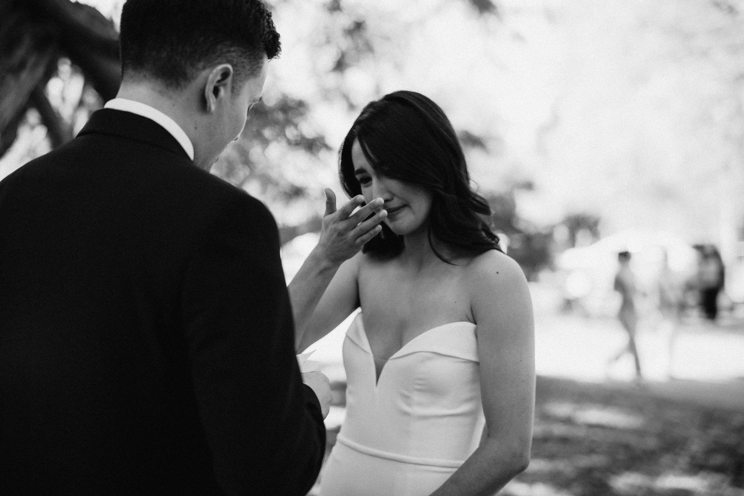A candid black and white wedding photo capturing a joyful moment between the bride and groom outdoors.