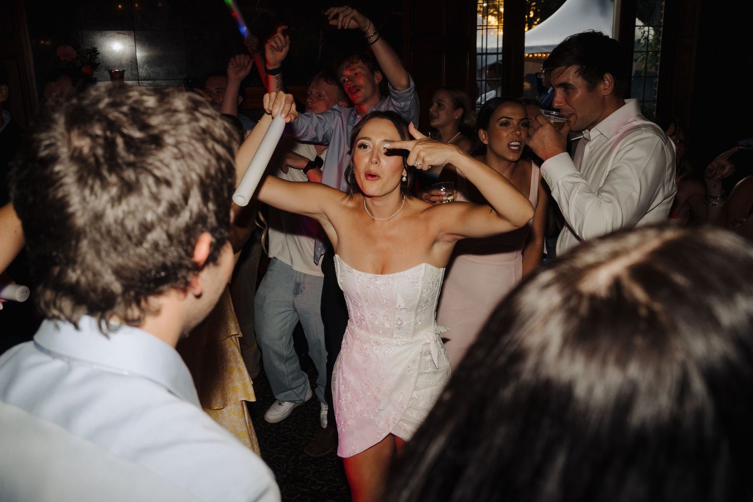 Dimly lit wedding reception dance floor filled with guests enjoying the celebration.
