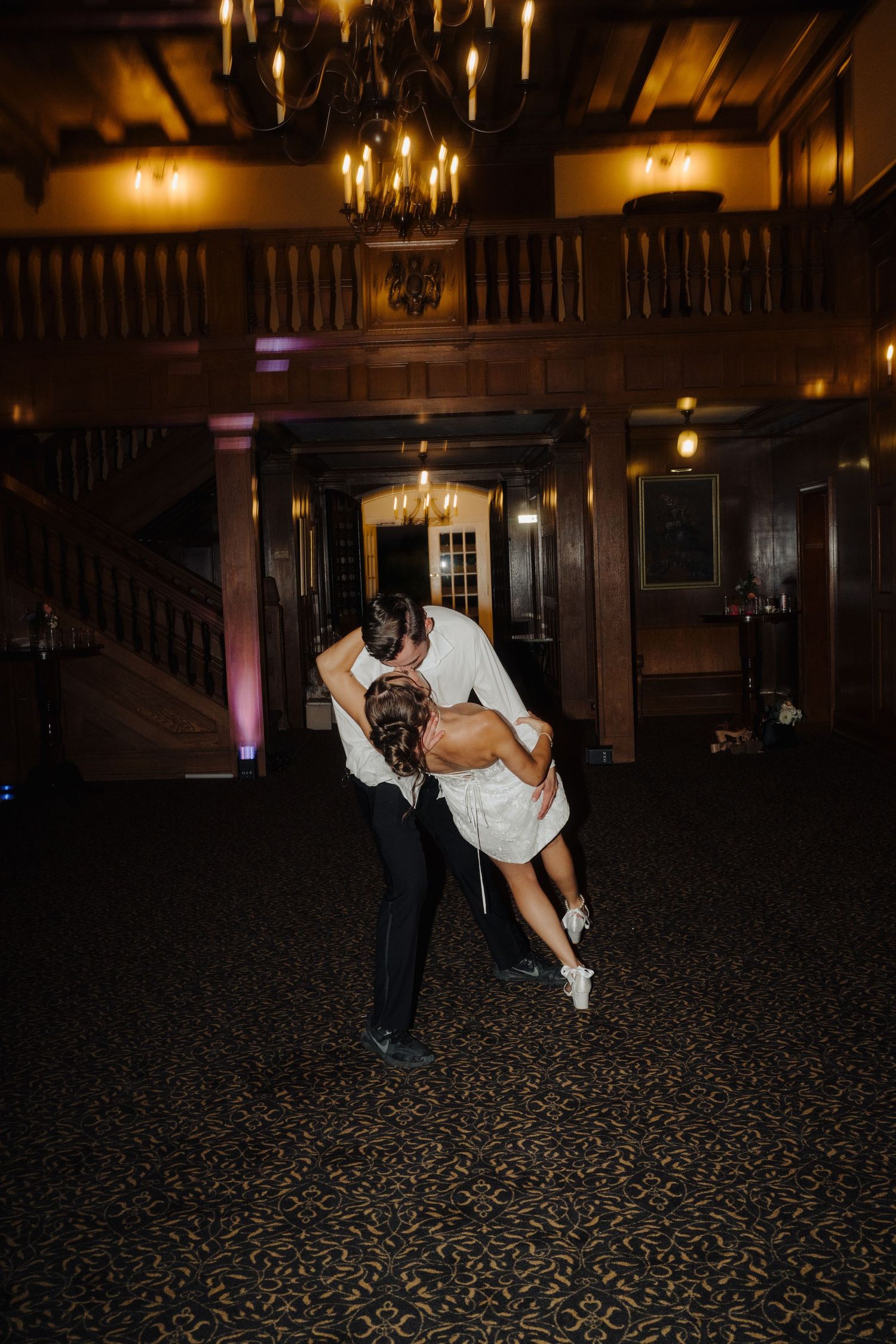 Romantic dance dip pose in an elegant venue with warm lighting and wooden details.